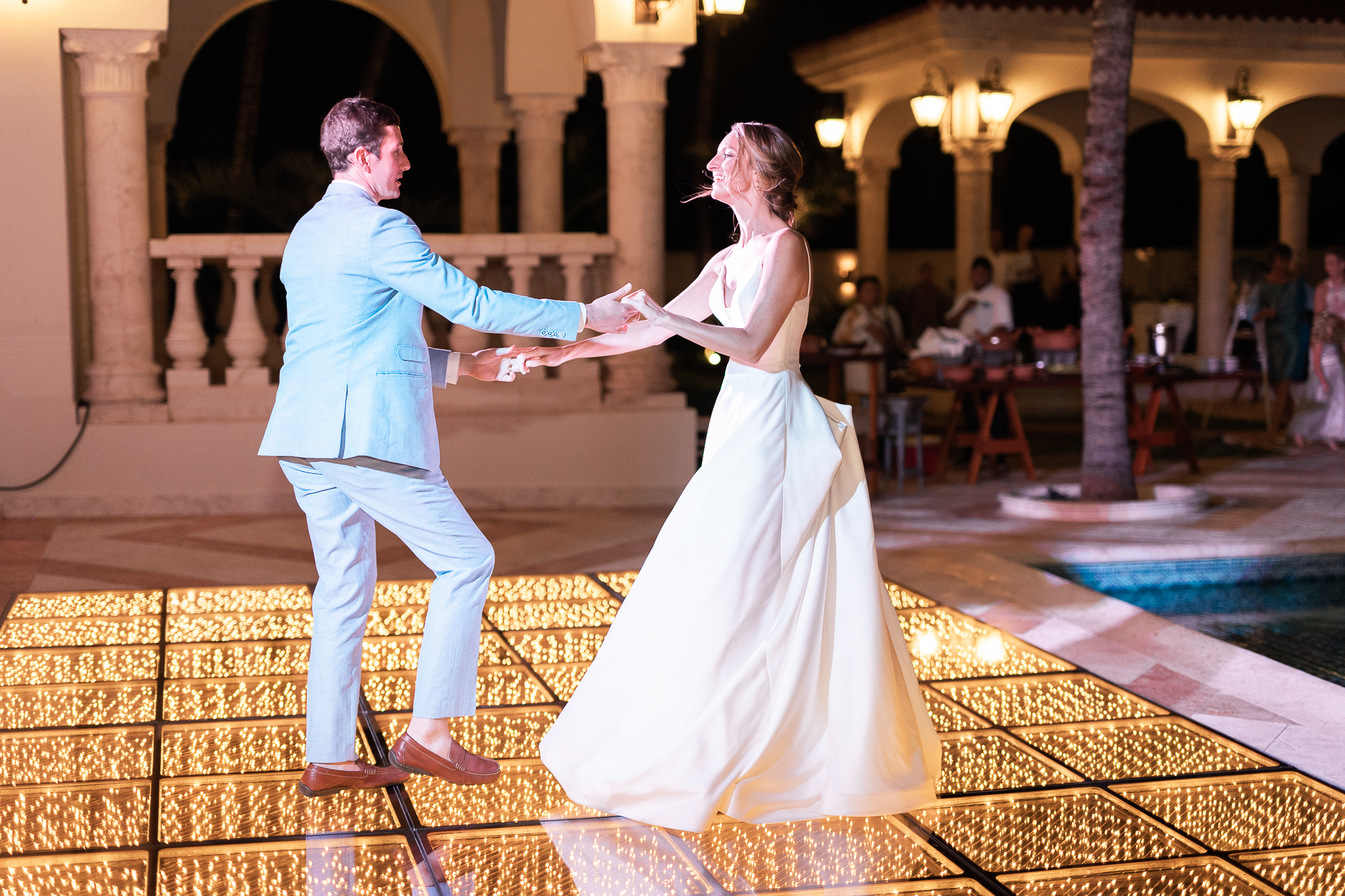 Bride and Groom share their first dance poolside at Villa La Joya, dancing on an Gold Infinity LED dance floor with lots of sparkle